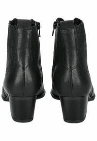 Bottines noires en cuir avec une texture lisse, des zips latéraux et un petit talon carré. Elles présentent des coutures verticales à l'arrière.