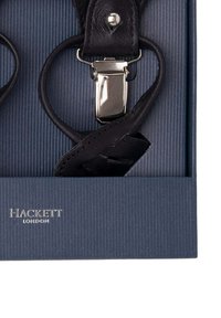 Zwarte leren bretels met zilveren metalen clips, tentoongesteld in een donkerblauwe doos met een gestreepte binnenkant. "HACKETT LONDON" in reliëf op de doos.