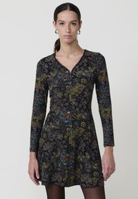 Vestido negro de mangas largas con escote en V, adornado con patrones florales multicolores y una silueta acampanada.