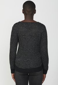 Maglione a maglia nero e argento con un motivo testurizzato, maniche lunghe, scollo ampio e polsini e orlo a costine. Design minimalista.
