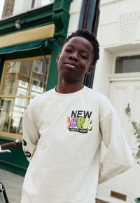 Lysegrå langærmet sweatshirt med farverige "NEW YORK" grafik foran og "SKATE OF MIND" tekst, med sorte accenter på ærmerne.