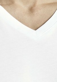 Maglietta bianca a V in cotone morbido, con una cucitura pulita attorno al collo e una consistenza morbida e uniforme in tutto il capo.