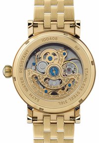 Montre en acier inoxydable doré avec un fond de boîtier transparent révélant un mouvement mécanique détaillé, dotée d'accents bleus et d'un design complexe.