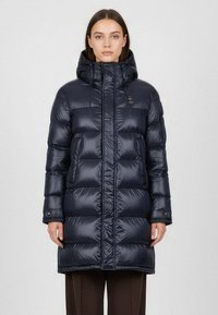 Námořnická pufovaná bunda s lesklým povrchem, do délky kolen, s vysokým límcem, předním zipovým zapínáním a dvěma velkými kapsami. Součástí je nastavitelná kapuce.