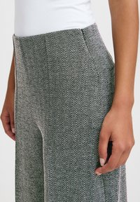 Grau-weiße gemusterte Hose mit Fischgrätenstruktur, seitlichen Taschen und einem hohen Taillendesign.