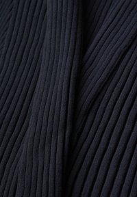 Gros plan sur un tissu tricoté côtelé bleu marine foncé montrant des lignes texturées verticales et des plis doux.