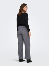 Black fitted long-sleeve top with textured ribbing; paired with light gray, loosely tailored pants featuring a subtle check pattern.