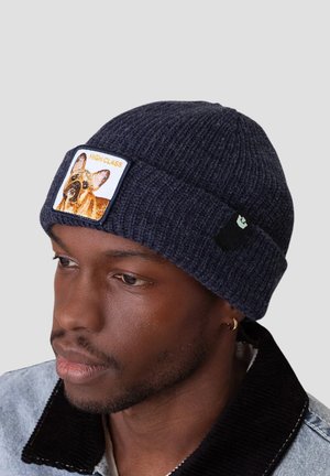 Bonnet en tricot côtelé bleu marine avec un patch brodé représentant un chien et le texte "HAUTE CATEGORIE". Étiquette de logo sur le côté visible.