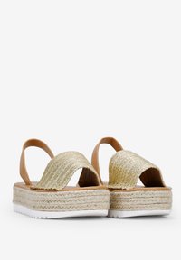 Sandalias de plataforma marrones con una correa de oro tejida. Presentan una suela envuelta en yute y una suela de goma blanca. Diseño de espalda abierta para un uso fácil.