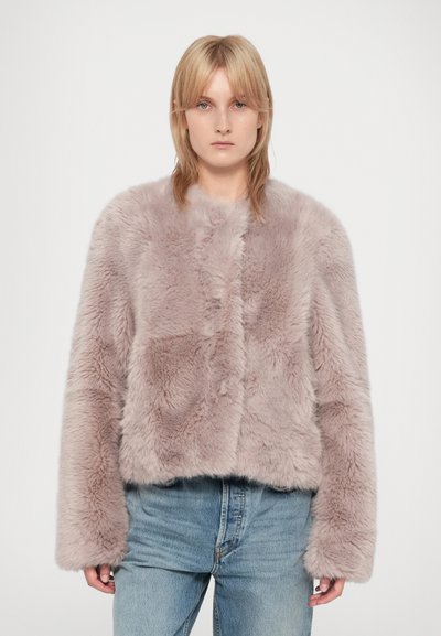 Short pink faux fur jacket with a cropped design, wide sleeves, and a soft texture, paired with light blue jeans.