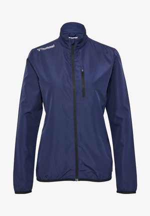 Veste légère bleu marine avec un col haut, fermeture éclair noire et une poche sur la poitrine. Fabriquée en tissu lisse, avec des poignets élastiques.