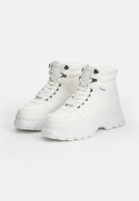 Zapatillas altas blancas con parte superior de cuero texturizado, cordones planos, ojales de metal y una suela de goma gruesa. Acentos de logo en el cuello.