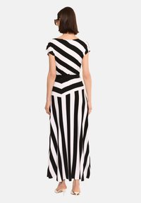 Czarna i biała pasiasta sukienka maxi z krótkimi rękawami, elastycznym pasem i rozkloszowaną spódnicą z wzorem zygzaka na dolnej krawędzi.