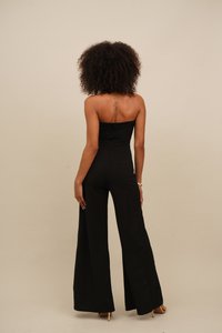 Black strapless jumpsuit with wide-leg pants, smooth fabric, and a fitted bodice. Features a zipper closure at the back.