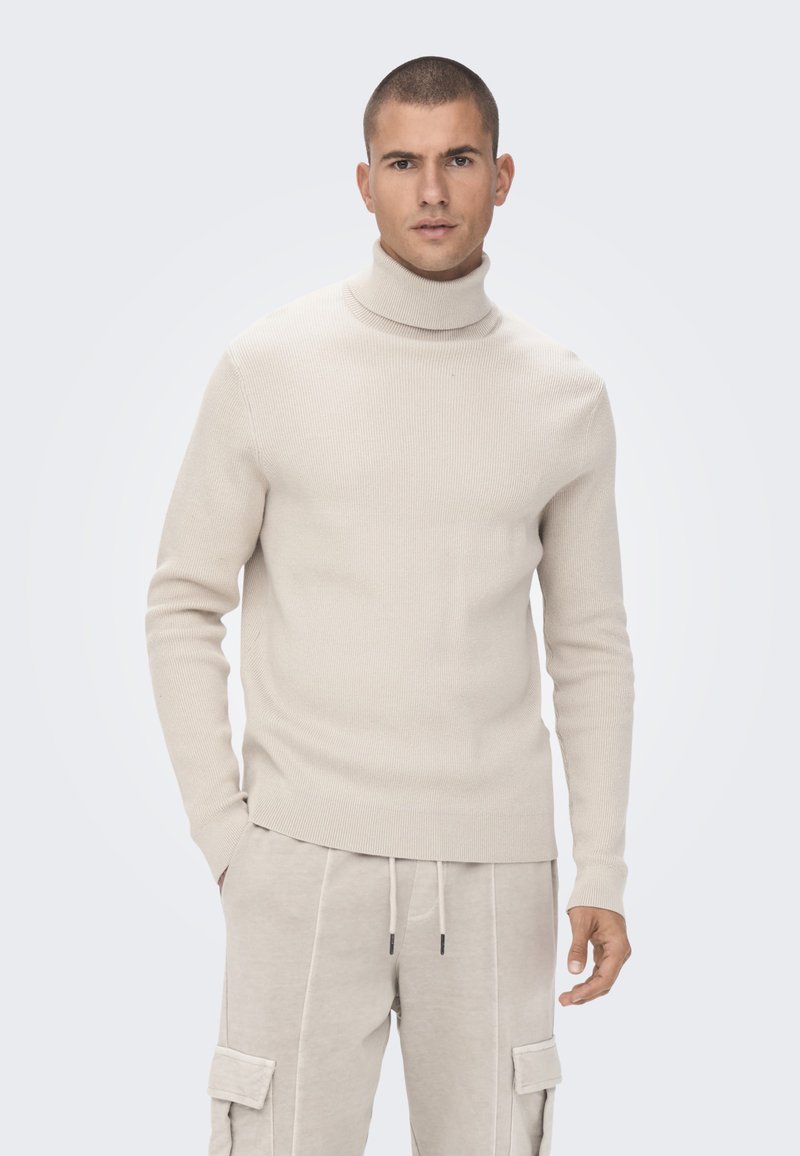 Beige gerippter Rollkragenpullover mit langen Ärmeln, verfügt über ein figurbetontes Design und eine weiche Textur, kombiniert mit hellbeigen Cargo-Hosen.