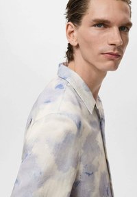 Kurzarmhemd aus leichtem Stoff mit einem blauem Aquarellmuster, klassischem Kragen und sichtbaren Nähten an den Schultern.