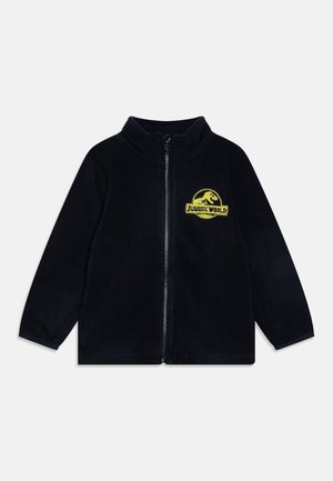 Veste polaire noire zippée avec manches longues et logo jaune Jurassic World sur la poitrine gauche.