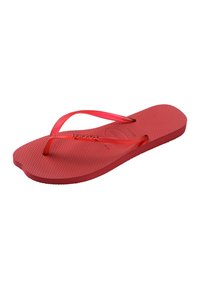 Une unique tong en caoutchouc rouge avec une semelle texturée et des fines bretelles en forme de Y sur fond blanc.