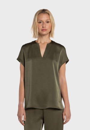 Haut à manches courtes couleur vert olive avec un décolleté en V et une coupe décontractée. Texture lisse, léger éclat, et petit logo discret à l'ourlet.