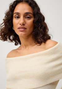 Crème off-shoulder trui van ribgebreide stof, met een zachte textuur en een losse pasvorm.