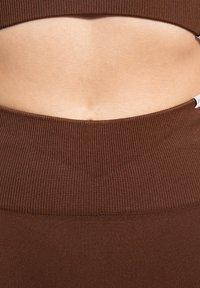 Hnědá proužkovaná látka, těsně přiléhající design s hladkou texturou, s širokým pasem nad pokožce tónovaným středem.