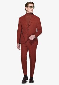 Rød skræddersyet jakkesæt med en struktureret turtleneck, slim-fit bukser, lapelkrave og runde solbriller. Glat stof med et moderne design.