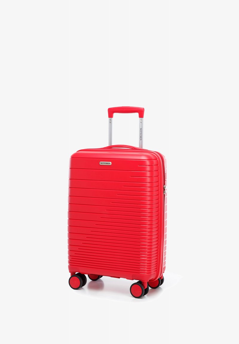 Valise rigide rouge avec des rainures horizontales, poignée rétractable, quatre roues jumelées à rotation multidirectionnelle et fermeture éclair. Texture lisse.