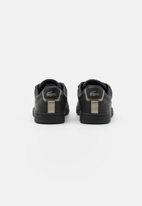 Svarta lädersneakers med en texturerad yta, som har metalliska accenter på hälen och varumärket. Låg design med en gummisula.