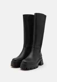 Black leather knee-high boots with a chunky rubber sole, featuring a sleek design and a side zipper for easy wear.