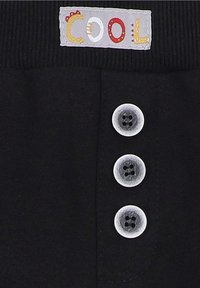 Schwarzer Stoff mit drei hellgrauen Knöpfen, mit einem Etikett, das "COOL" in bunten Buchstaben sagt. Texturiertes Taillenbund, schlichtes Design.