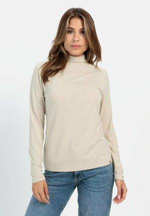 Beige langærmet turtleneck skjorte i blødt stof, med en tætsiddende pasform og en subtil tekstur. Bæres sammen med blå jeans.