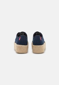 Navy canvas platform shoes with woven jute soles. Features a round toe and back heel detail, accented with a small red label.