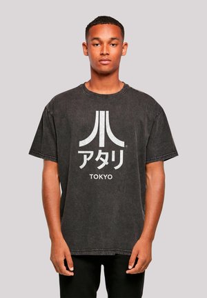 Black oversized t-shirt made of cotton, featuring a prominent white Atari logo and Japanese text "TOKYO" printed on the front.