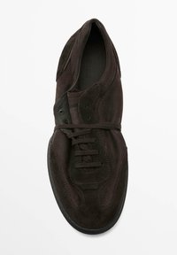 Brun mockasneaker med rundad tå, snörning, kontrasterande sömmar och gummisula. Mjuk textur med minimalistisk design.