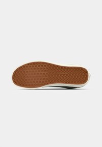 Rubber sneaker sole in brown with a patterned grip. The edge features a white border, showcasing a durable design for traction and support.