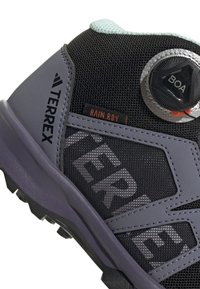 Grau und schwarzer Wanderschuh mit Mesh-Obermaterial, Boa-Schnürsystem, auffälligem Logo und robustem Profil, das für Haftung auf verschiedenen Oberflächen ausgelegt ist.