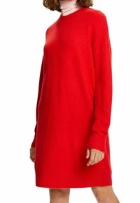 Czerwona dzianinowa sukienka wykonana z miękkiej tkaniny, o luźnym kroju, z długimi rękawami i okrąg�łym dekoltem. Gładka faktura z prążkowanymi mankietami.