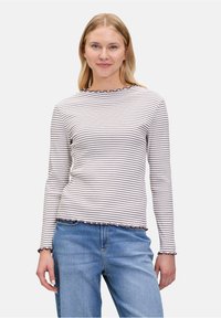 Langärmeliges gestreiftes Hemd in Weiß und Dunkelnavy, mit einem gewellten Ausschnitt und Saum. Leichtes, tailliertes Design. Tragen mit blauen Denim-Hosen.