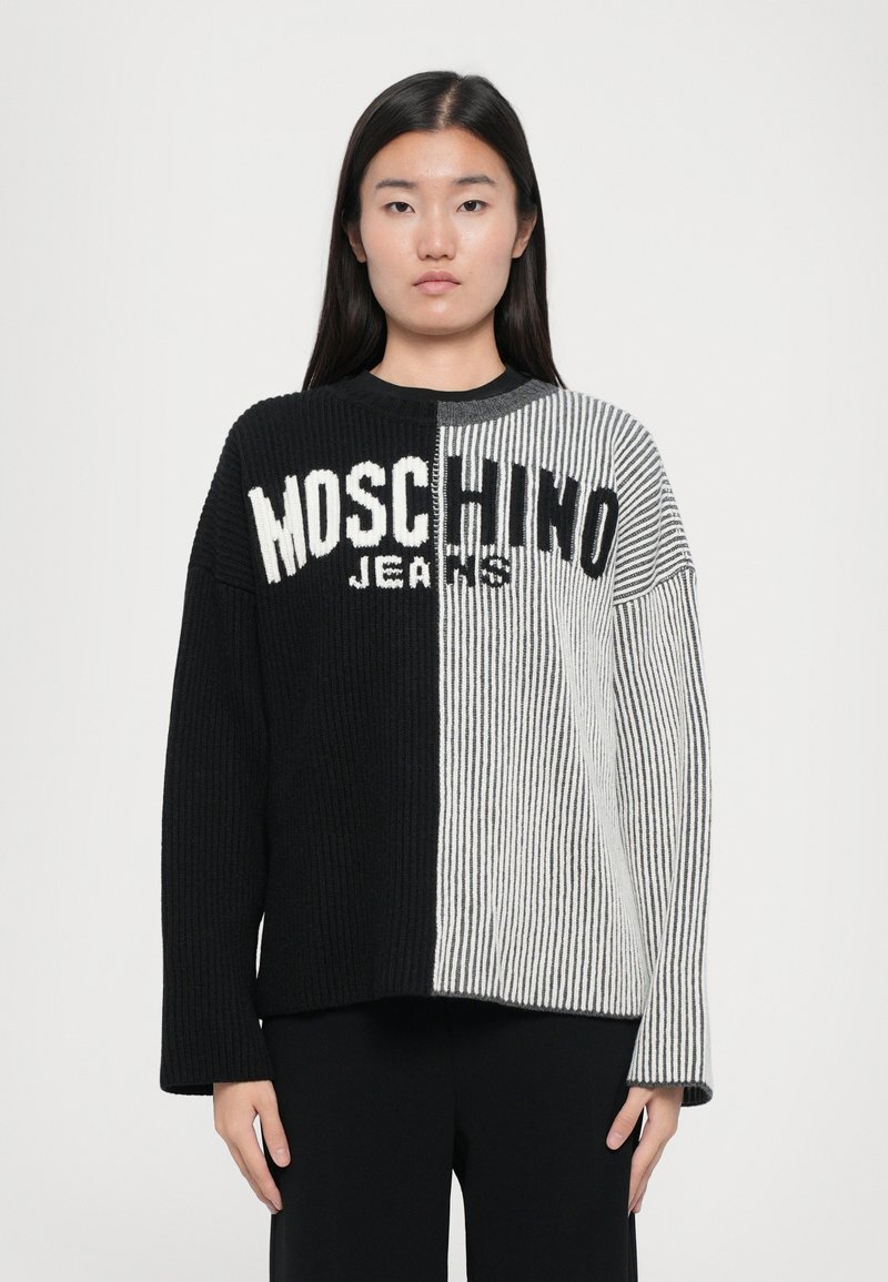 Megztinis su juodais ir pilkais dryžiais, ant kurio bold ryškiomis baltomis raidėmis parašyta "Moschino Jeans". Susikaupus tekstūra, ilgomis rankovėmis, apvaliu kaklu.