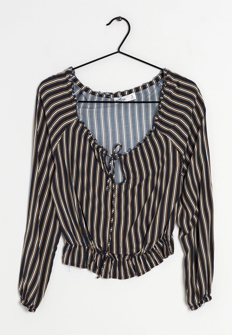 Blouse rayée avec un fond bleu marine, présentant des rayures étroites alternées en bleu clair et en jaune, avec un col froncé et un ourlet élastiqué.
