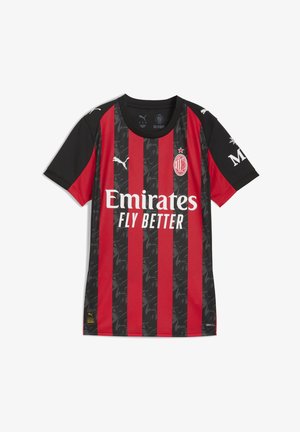 Czerwona i czarna koszulka piłkarska w paski, z okrągłym dekoltem, z geometrycznym wzorem, logo na piersi oraz tekstem sponsora.