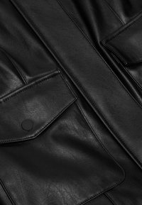 Černá kožená bunda s dvěma předními kapsami na klopy se zapínáním na patentky, hladkou texturou a čistým prošíváním.