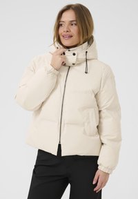 Kreminės spalvos pūkinė striukė su užtrauktuku, reguliuojama kapučino, elastinėmis rankovėmis ir šoninėmis kišenėmis. Lygus paviršius, pūkuotas dizainas.