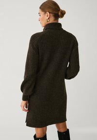 Rippedes, dunkelbraunes Strickkleid mit hohem Kragen und langen, gepufften Ärmeln, das einen seitlichen Schlitz am Saum und eine weiche Textur aufweist.