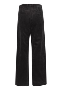 Pantalon large en velours côtelé noir avec poches passepoilées à l'arrière et passants pour ceinture, vu de dos sur un fond blanc.