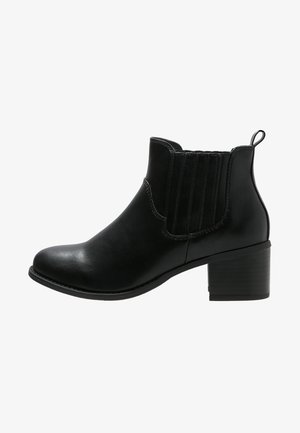 Botines negros de cuero liso, con paneles elásticos a los lados, puntera redonda y tacón bajo tipo bloque. Diseño simple y elegante.