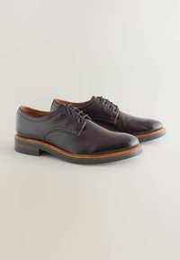 Pantofi din piele de culoare burgundy închis, cu o finisare netedă, vârful rotund, design cu șireturi și o talpă contrastantă de culoare marron. Detalii minime de cusătură.