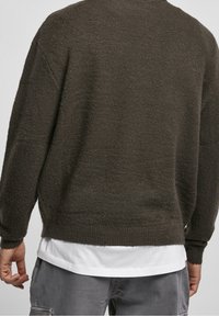 Maglione verde scuro realizzato in tessuto a maglia testurizzato, con una vestibilità rilassata, maniche larghe e polsini e orlo a coste.
