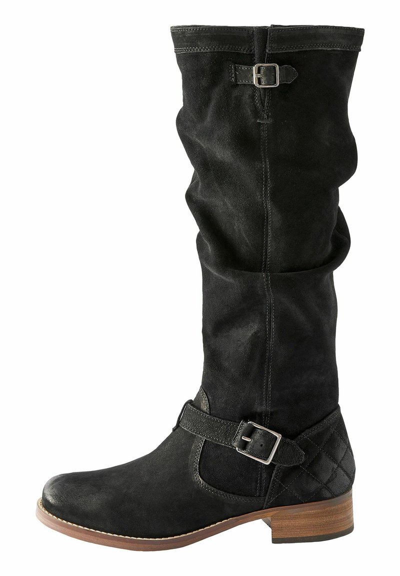 Botte noire en suède, haute jusqu'au genou, avec un design flou, une sangle avec une boucle en argent et un accent texturé au niveau de la cheville. Talon en bois.