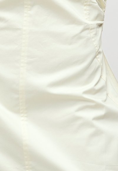 Κοντινή λήψη λεπτής, εκρού υφάσματος με ορατή ραφή και ελαφριά υφή ζάρας.